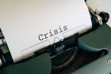 Picture of a typewriter printing out a picture of the word "crisis."